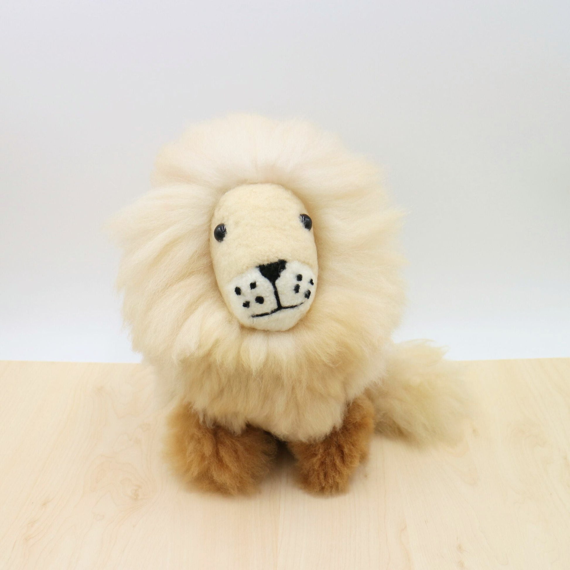 Handcrafted alpaca stuffed animal lion with fluffy cream mane, brown body, and adorable embroidered face. Eco-friendly, fair trade plush toy made from natural, sustainable materials. Perfect for cuddling or home decor.