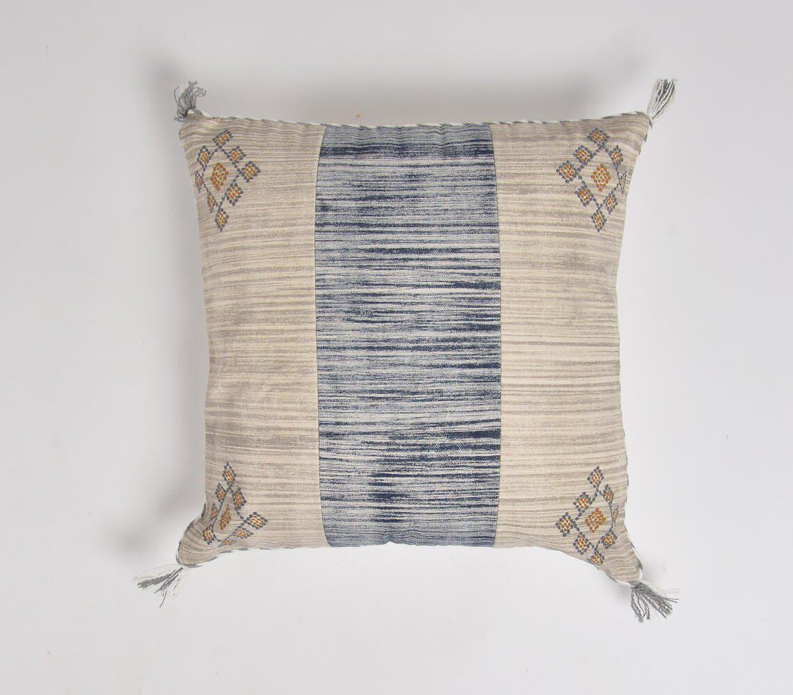 Square cushion cover with beige and blue striped pattern, featuring embroidered geometric designs in corners and decorative tassels. Handcrafted coastal-inspired textile with a blend of traditional and contemporary style.