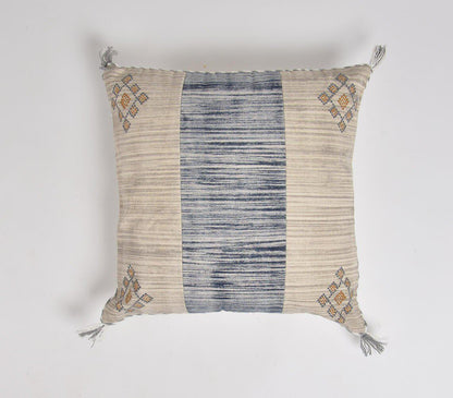 Square cushion cover with beige and blue striped pattern, featuring embroidered geometric designs in corners and decorative tassels. Handcrafted coastal-inspired textile with a blend of traditional and contemporary style.