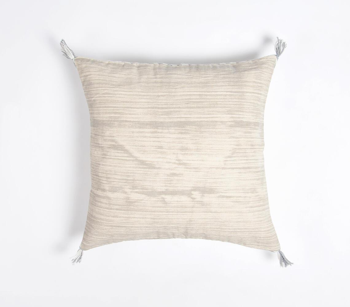 Minimalist square cushion cover in light beige with subtle texture, featuring white tassels on corners. Handcrafted cotton fabric with a hidden zipper, showcasing elegant simplicity for modern home decor.